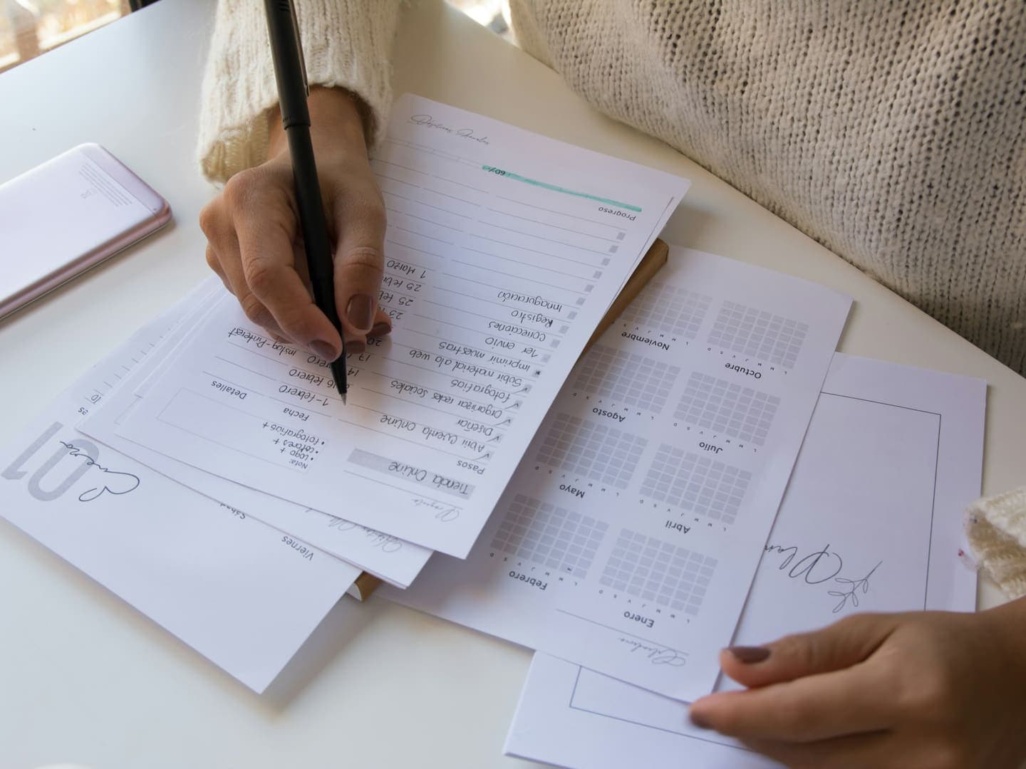 Des mains remplissent des formulaires au stylo sur un bureau clair
